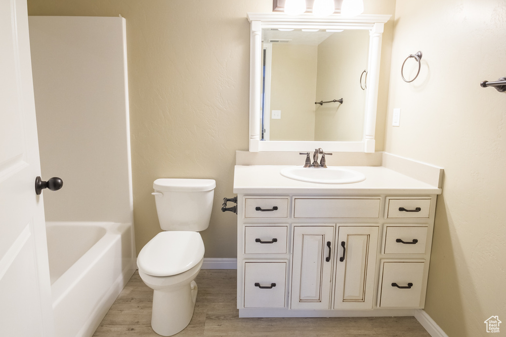 Full bathroom with shower / bathing tub combination, toilet, oversized vanity, and hardwood / wood-style floors