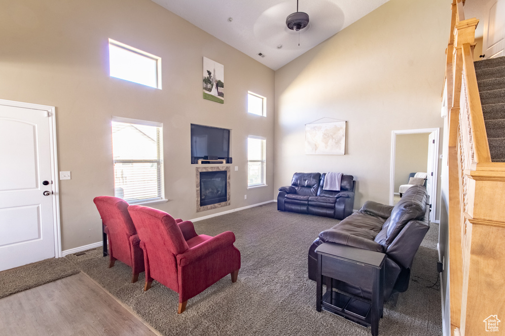 Carpeted living room with ceiling fan and high vaulted ceiling