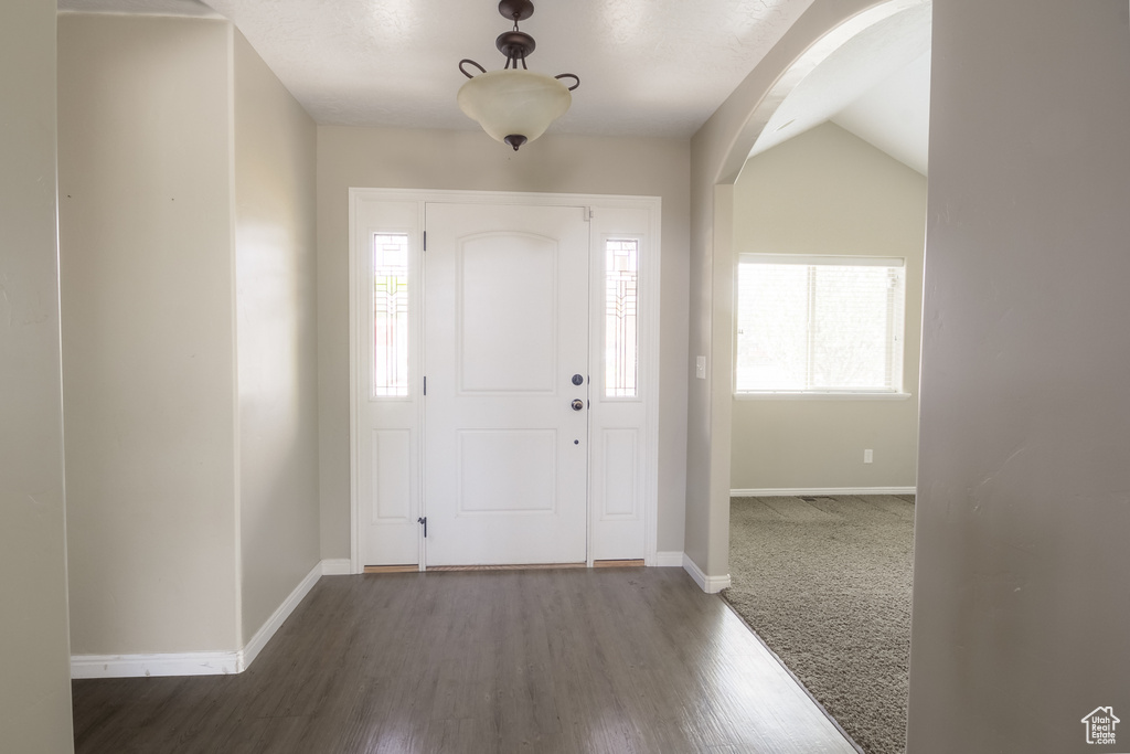 Carpeted foyer entrance with lofted ceiling