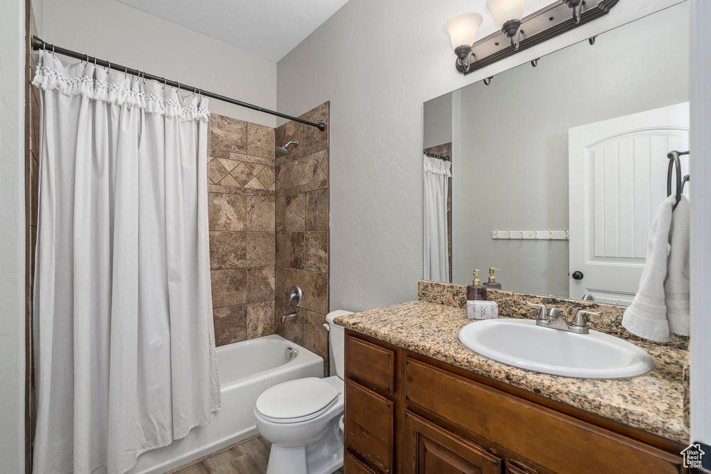 Full bathroom featuring hardwood / wood-style flooring, toilet, vanity, and shower / tub combo with curtain