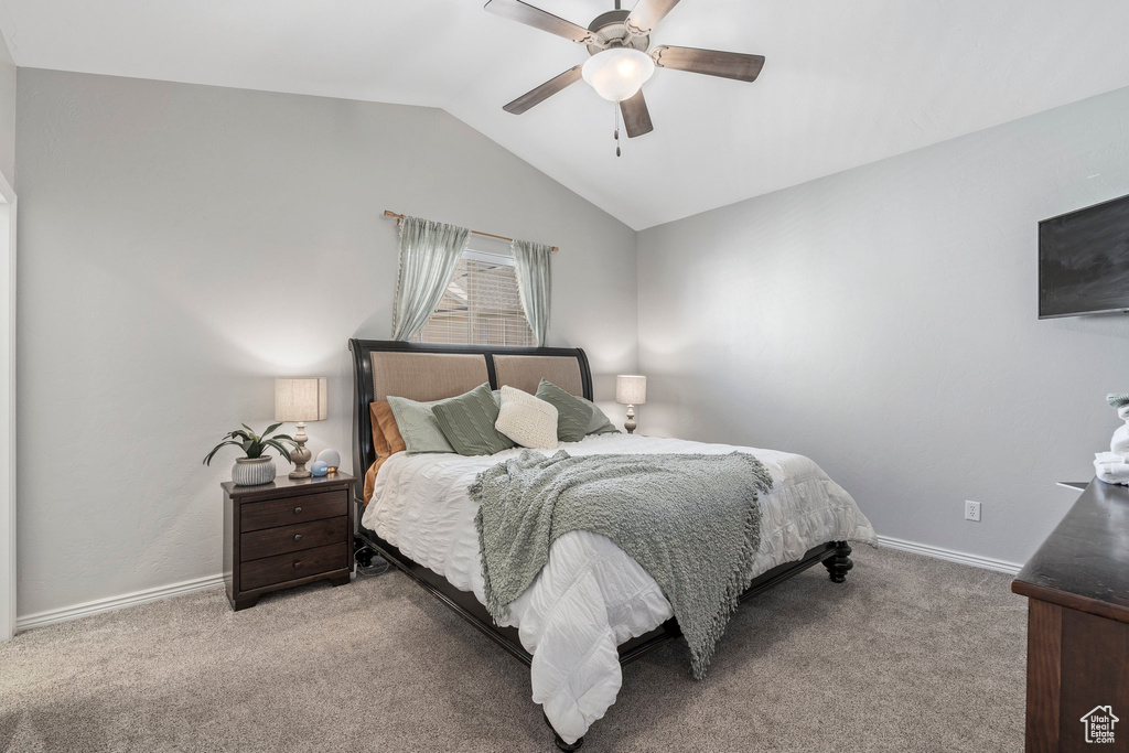 Carpeted bedroom featuring vaulted ceiling and ceiling fan