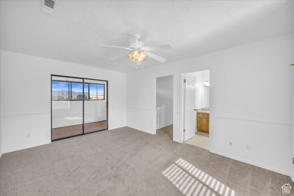 Unfurnished bedroom featuring light colored carpet, ceiling fan, ensuite bathroom, and a closet