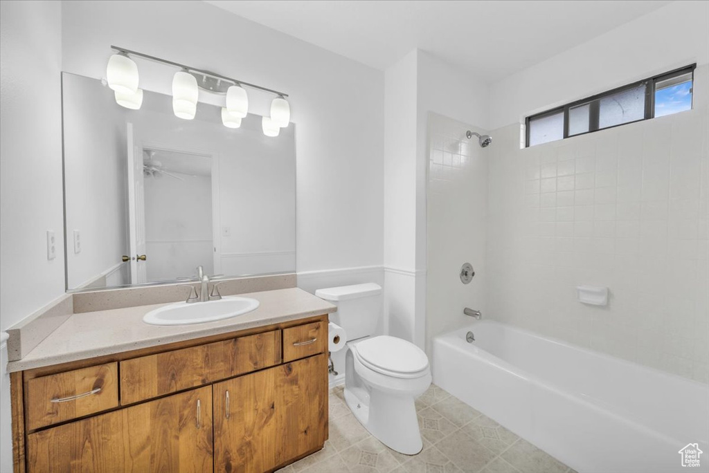 Full bathroom with ceiling fan, tiled shower / bath, tile floors, toilet, and vanity