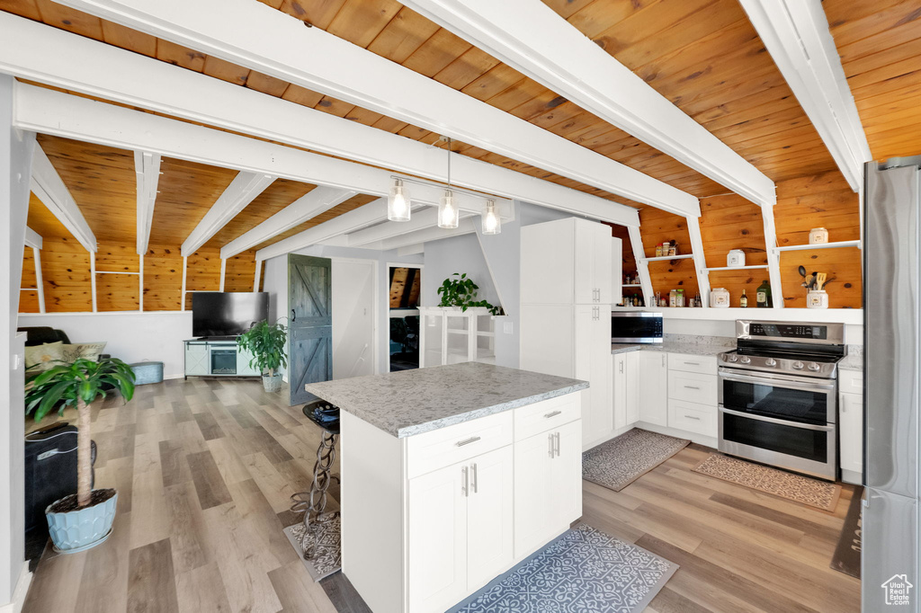 Kitchen featuring beamed ceiling, appliances with stainless steel finishes, white cabinetry, decorative light fixtures, and wooden ceiling