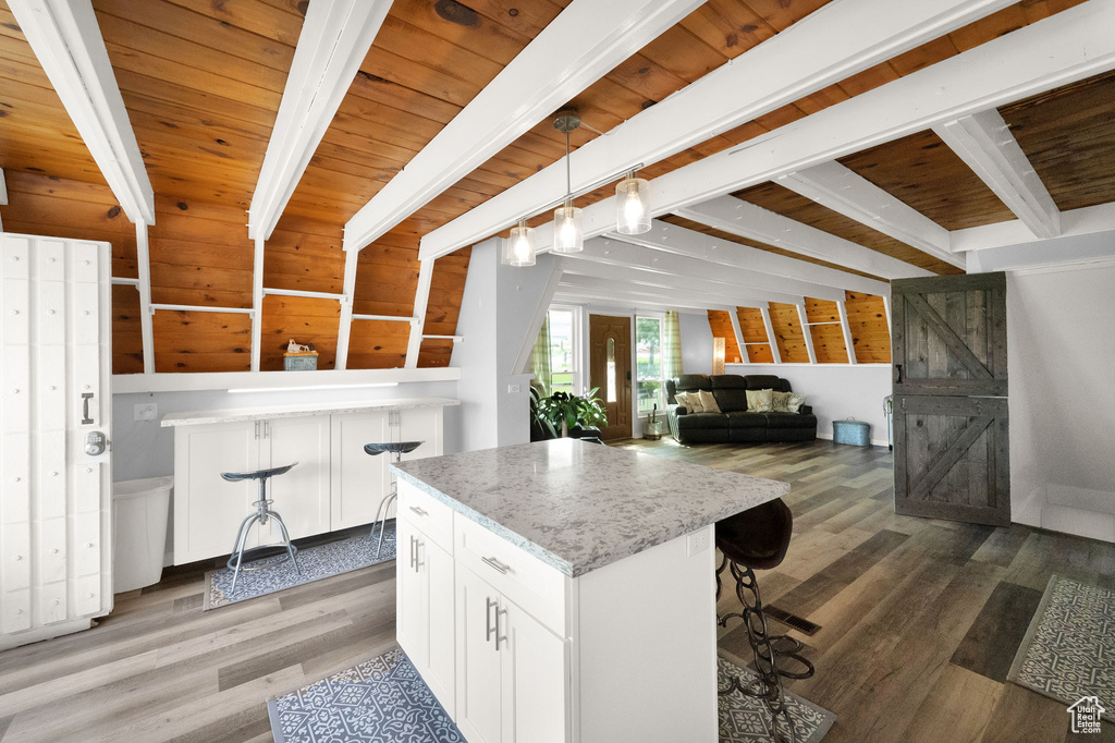 Kitchen featuring hanging light fixtures, wood-type flooring, beam ceiling, white cabinetry, and wood ceiling