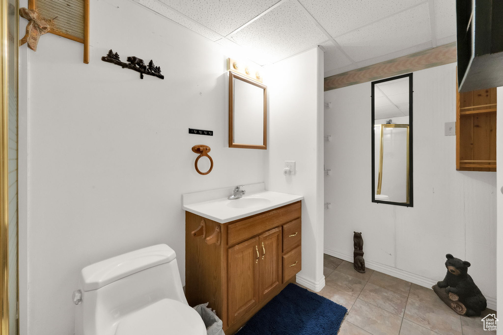 Bathroom with tile flooring, a drop ceiling, oversized vanity, and toilet