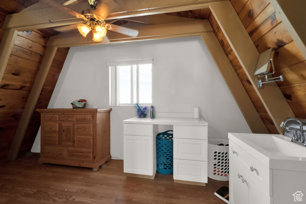 Bonus room with wood walls, ceiling fan, sink, and dark hardwood / wood-style flooring