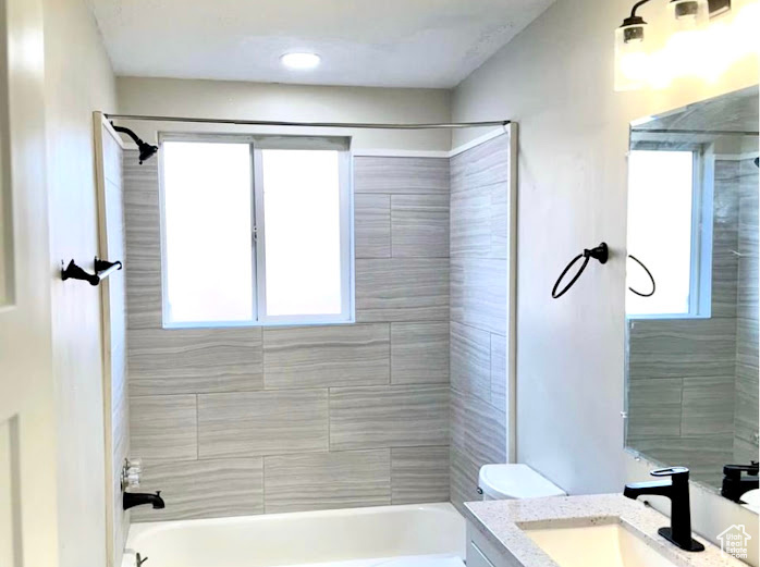 Full bathroom featuring tiled shower / bath combo, vanity, and toilet