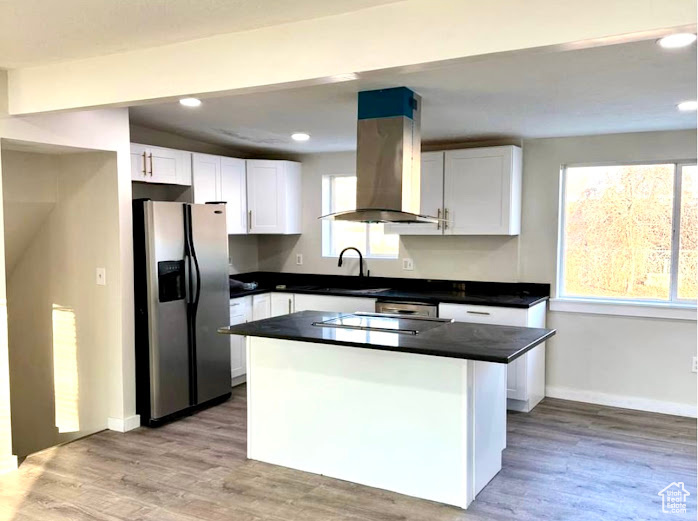 Kitchen featuring white cabinets, island exhaust hood, light wood-type flooring, and stainless steel refrigerator with ice dispenser