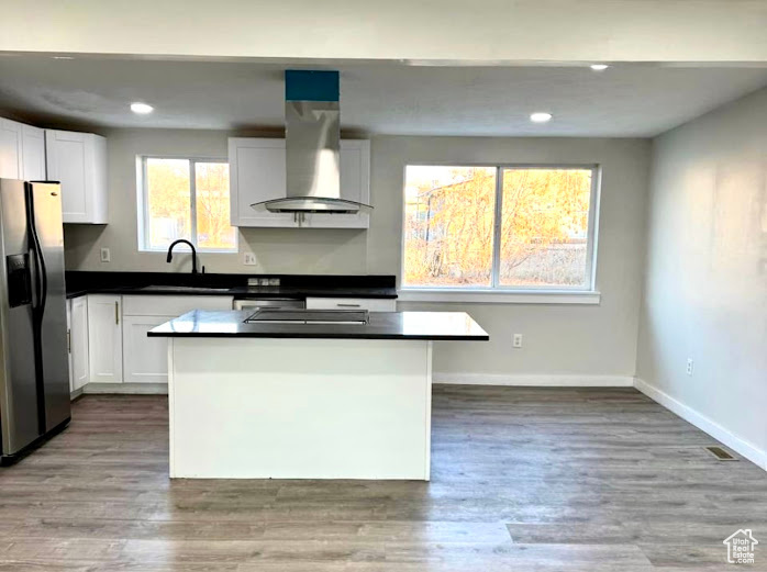 Kitchen featuring a kitchen island, white cabinets, light wood-type flooring, stainless steel fridge with ice dispenser, and island exhaust hood