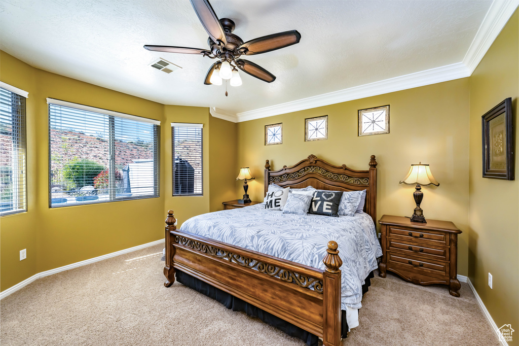Carpeted bedroom with ornamental molding and ceiling fan