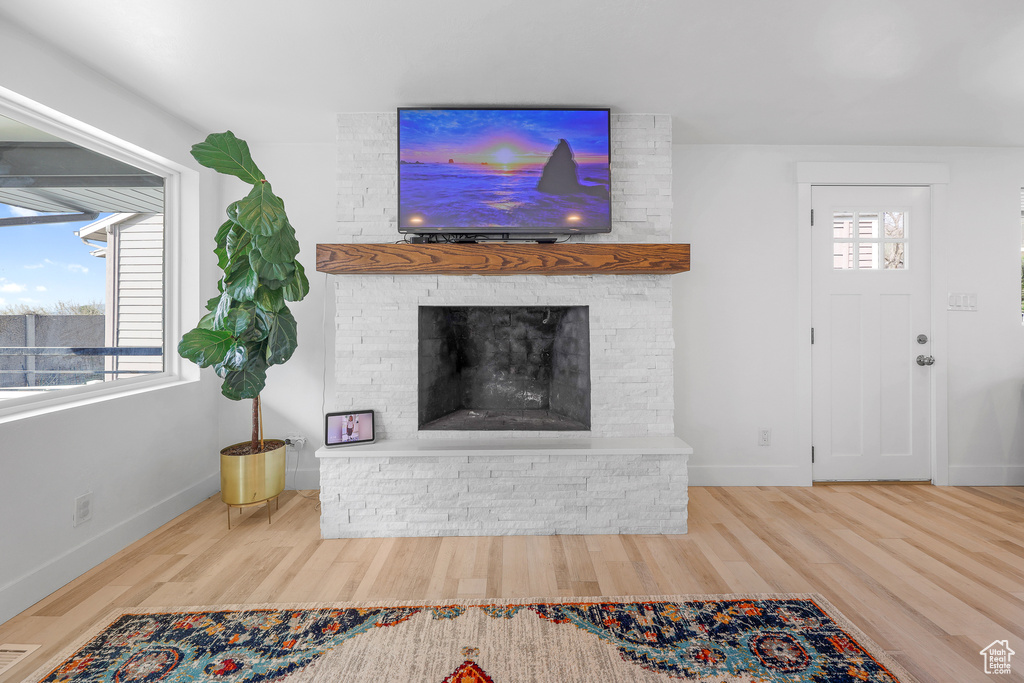 Living room featuring a large fireplace, light hardwood / wood-style floors, and brick wall