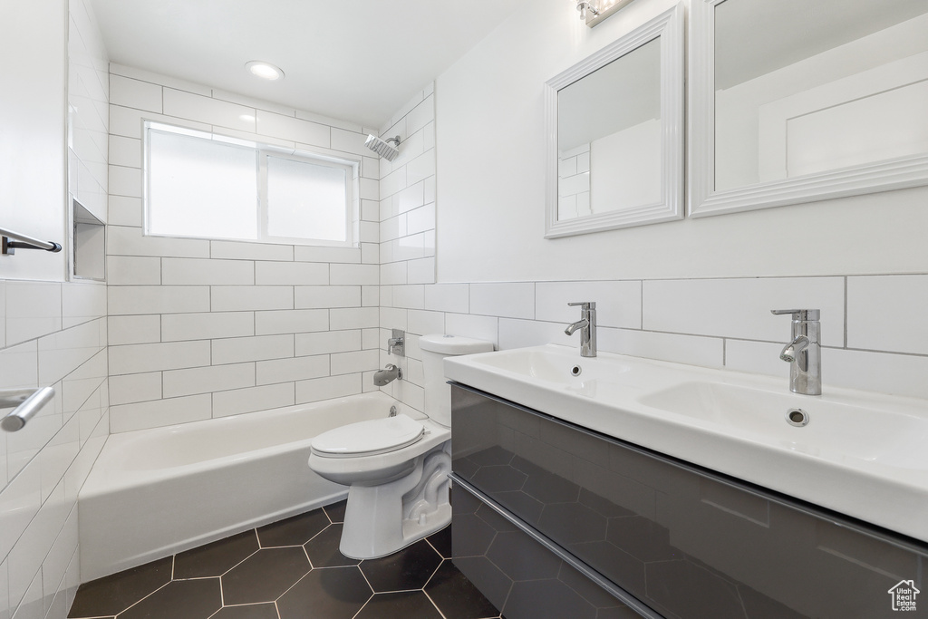 Full bathroom with tile floors, tiled shower / bath, toilet, and tile walls