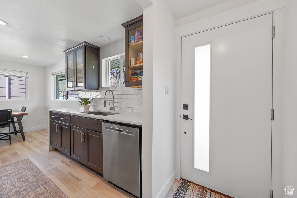 Kitchen featuring dark brown cabinets, backsplash, light hardwood / wood-style floors, sink, and stainless steel dishwasher