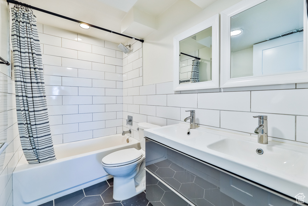 Full bathroom with tile walls, shower / bathtub combination with curtain, backsplash, toilet, and tile flooring