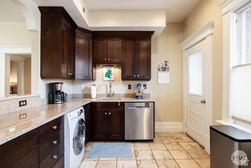 Kitchen featuring light tile floors, sink, washer / dryer, stainless steel dishwasher, and light stone countertops
