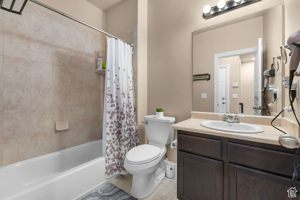 Full bathroom with large vanity, tile floors, toilet, and shower / bath combo with shower curtain