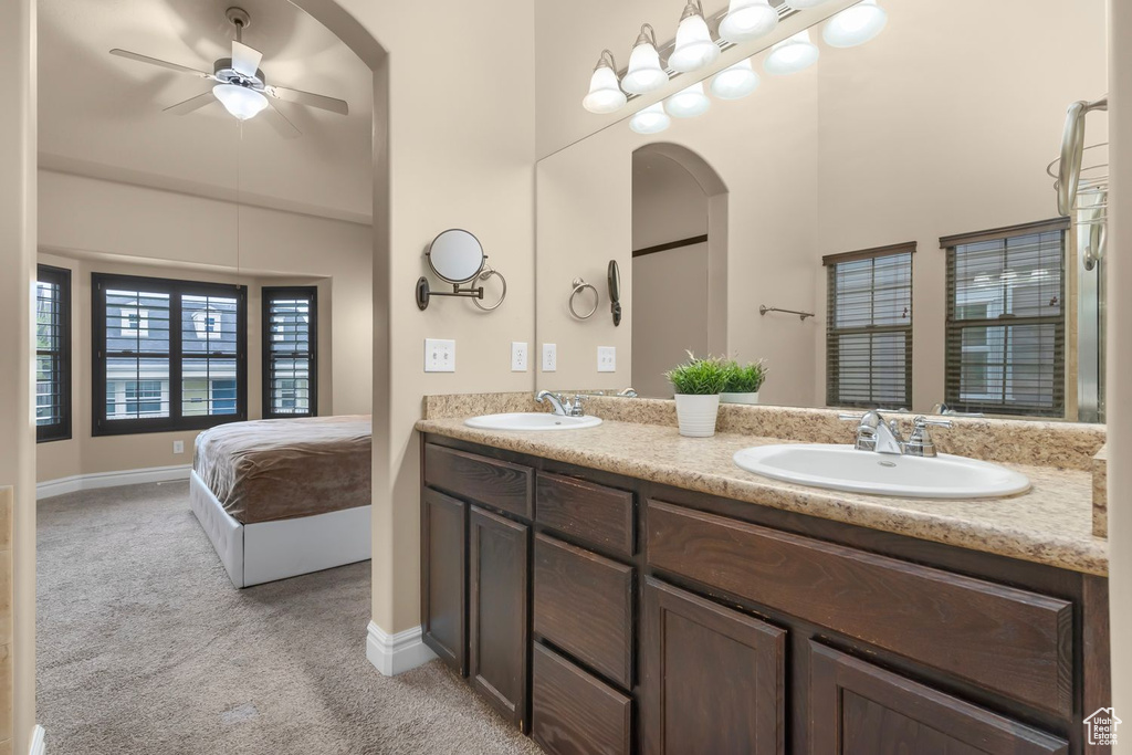 Bathroom featuring double sink vanity, ceiling fan, and a high ceiling