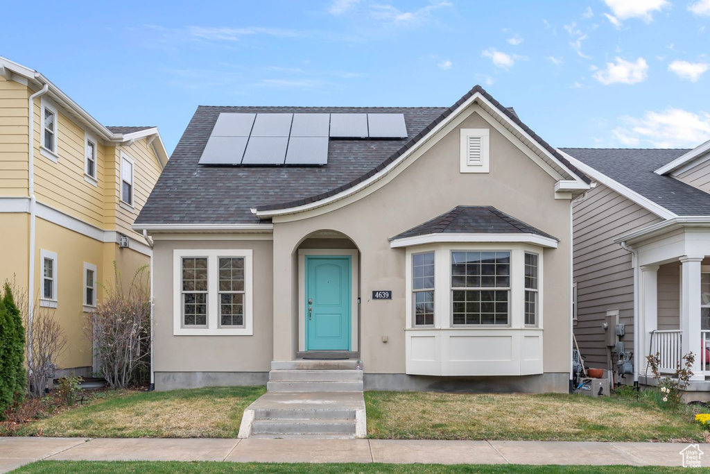 View of front of home featuring solar panels and a front yard