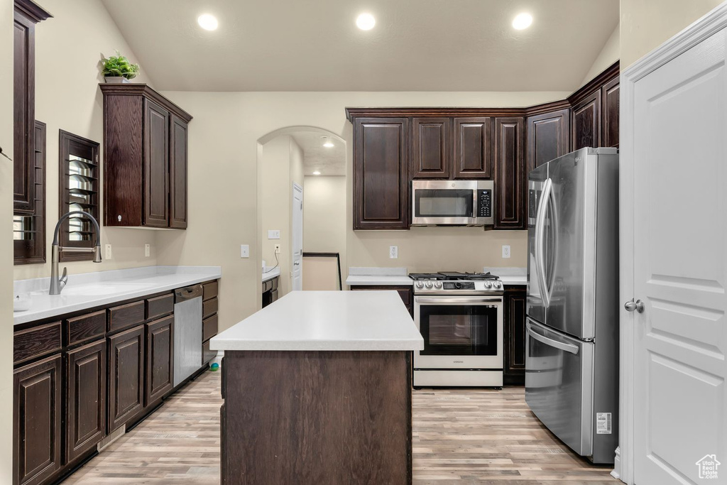 Kitchen featuring a center island, appliances with stainless steel finishes, light hardwood / wood-style floors, and dark brown cabinets
