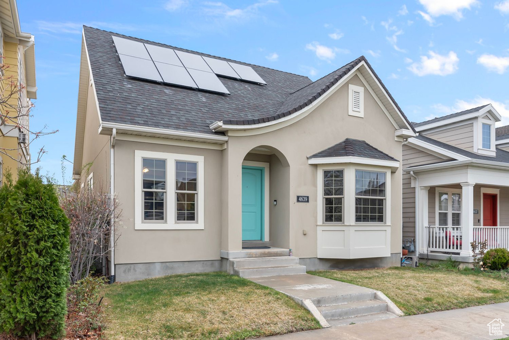 View of front of home with a front lawn and solar panels
