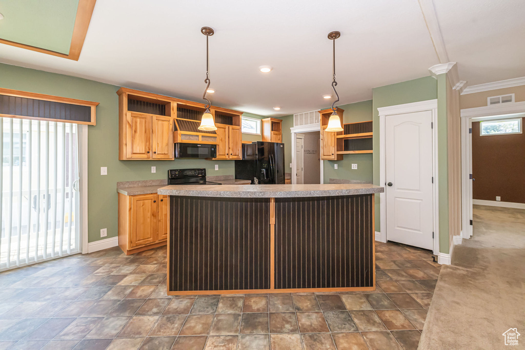 Kitchen featuring dark colored carpet, a kitchen island, black appliances, pendant lighting, and ornamental molding