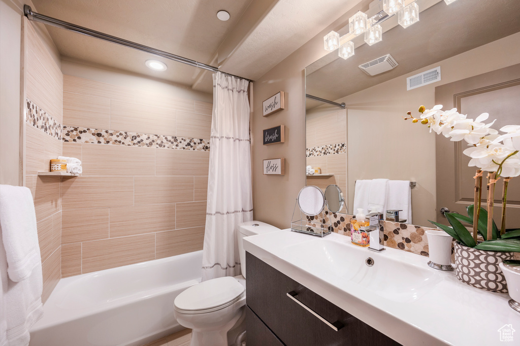 Full bathroom with oversized vanity, toilet, and shower / tub combo with curtain