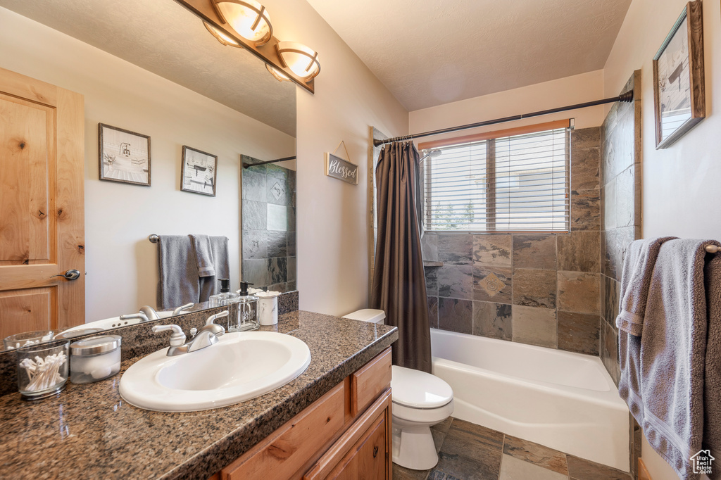 Full bathroom featuring tile flooring, vanity with extensive cabinet space, shower / bath combination with curtain, and toilet