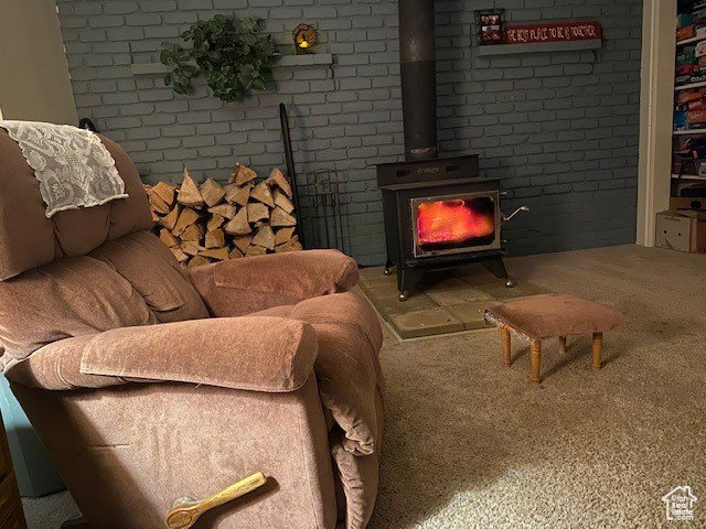 Carpeted living room with a wood stove and brick wall