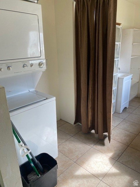 Laundry room with stacked washer and dryer and light tile floors