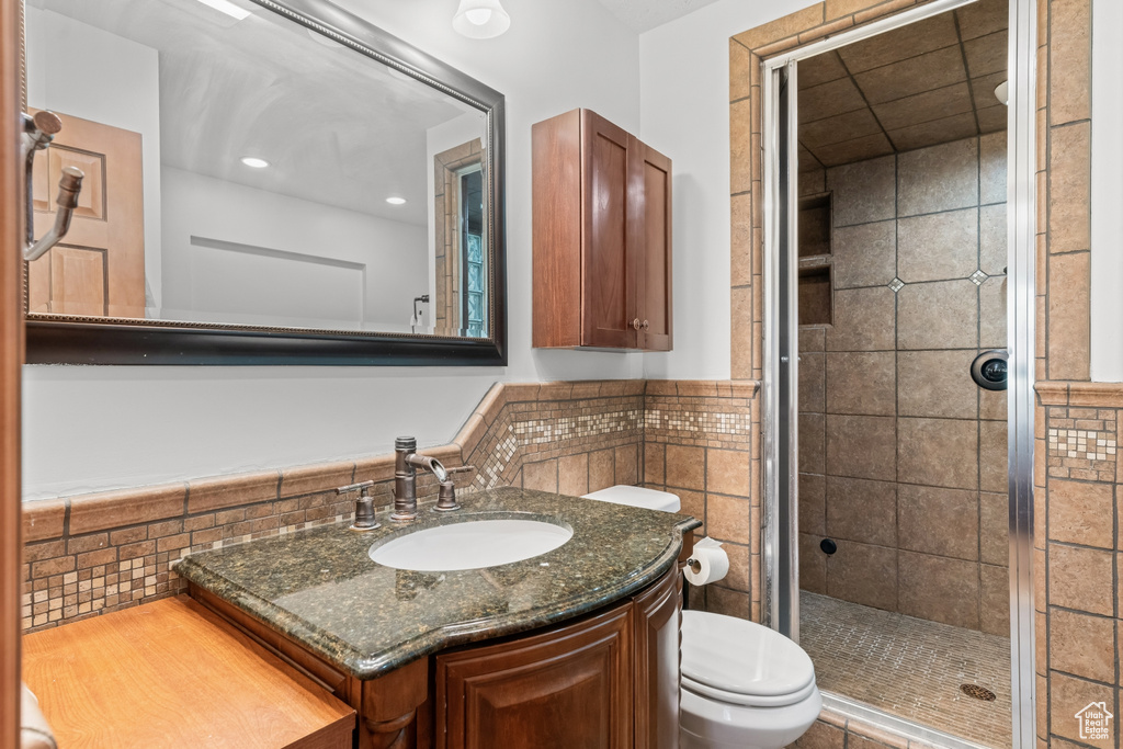 Bathroom featuring backsplash, vanity, toilet, and tiled shower