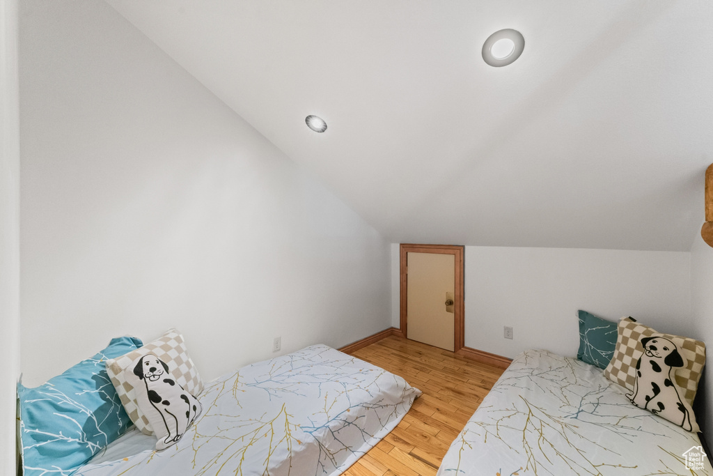 Bedroom with light hardwood / wood-style floors and vaulted ceiling
