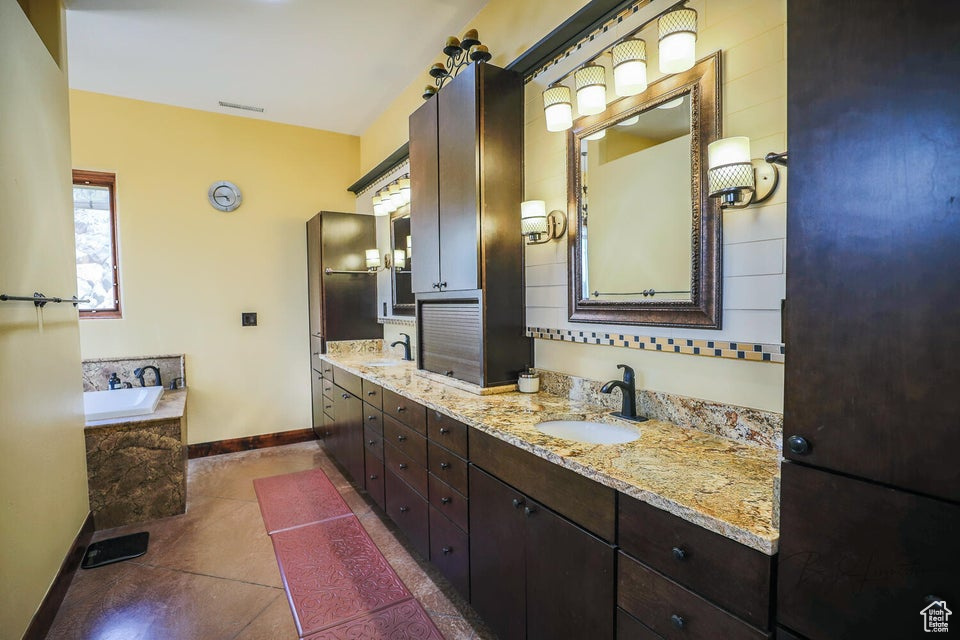Bathroom with tile floors, tiled bath, and dual bowl vanity