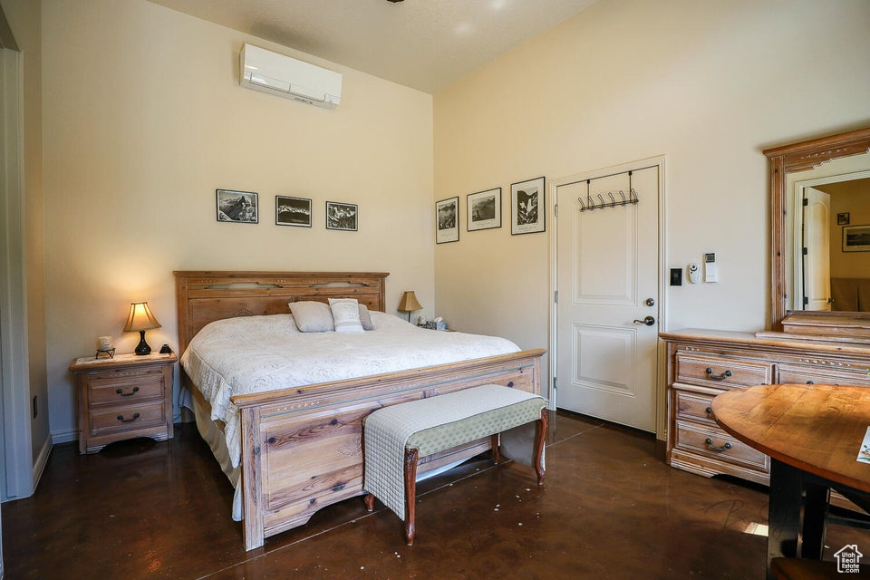 Bedroom featuring a wall mounted AC and a towering ceiling