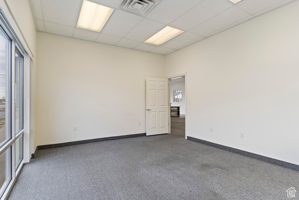 Unfurnished room featuring a drop ceiling and dark carpet