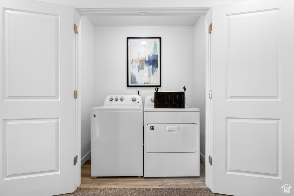 Washroom with hardwood / wood-style floors and washer and dryer