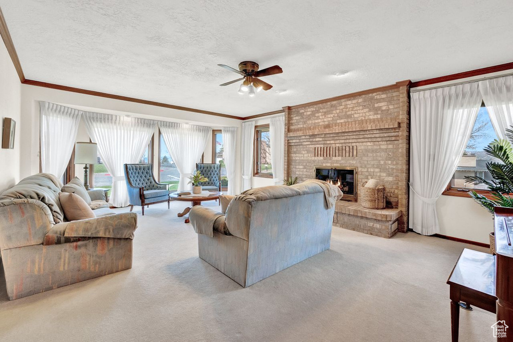 Living room featuring a wealth of natural light, light carpet, ceiling fan, and a fireplace