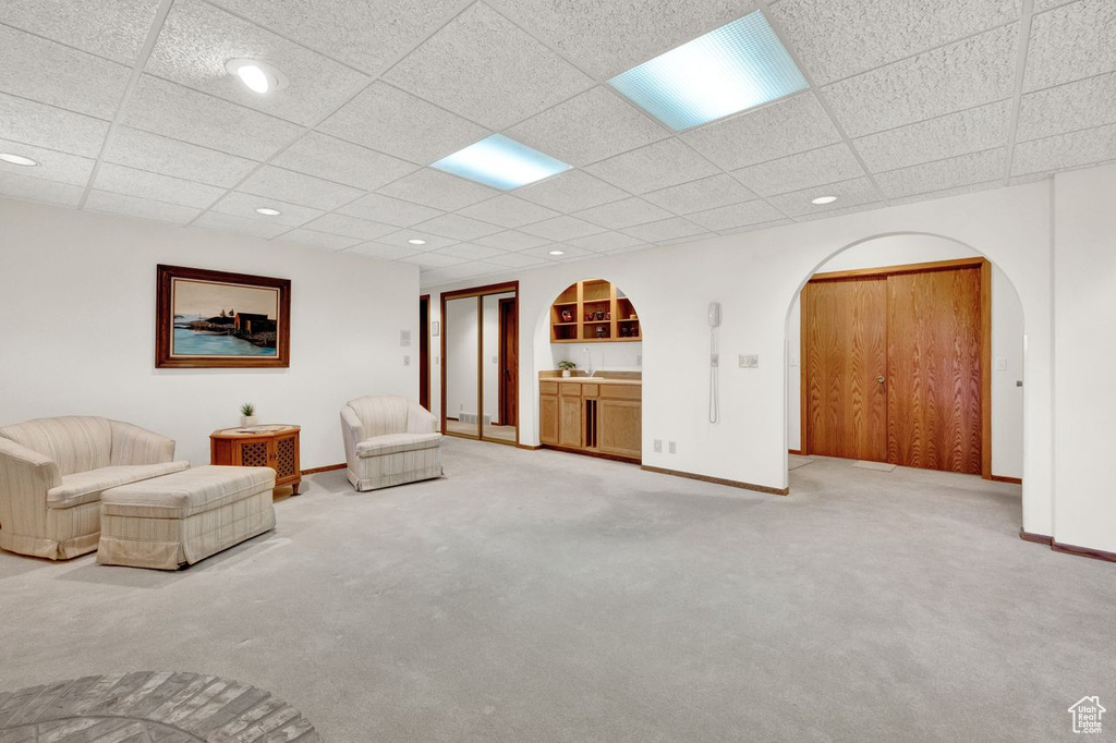 Unfurnished living room featuring a drop ceiling and light carpet