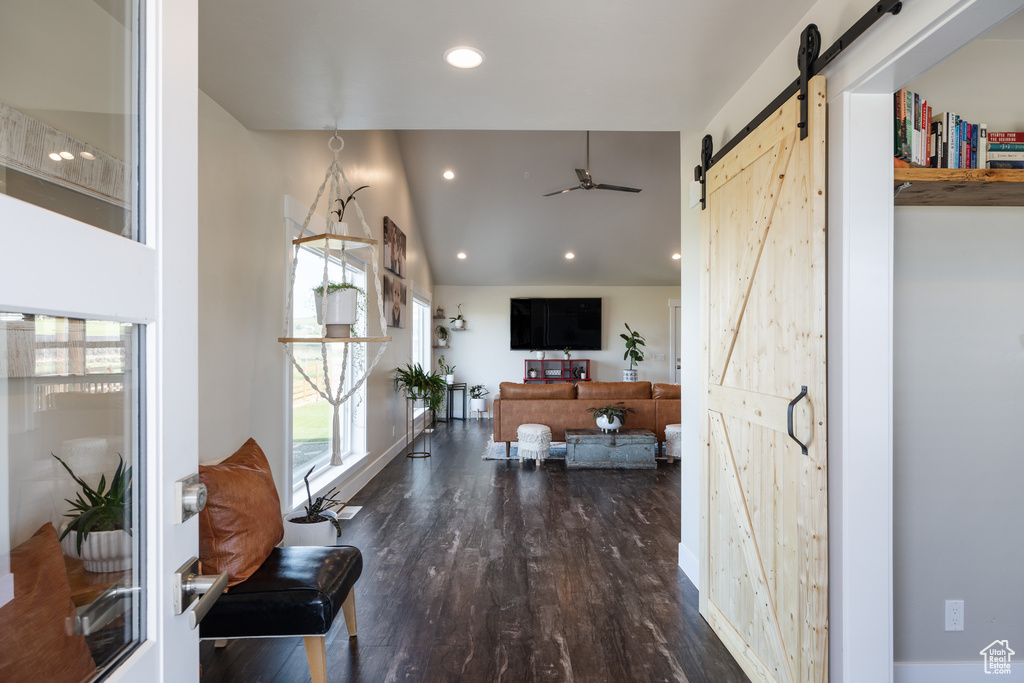 Interior space featuring ceiling fan, a barn door, and dark hardwood / wood-style floors