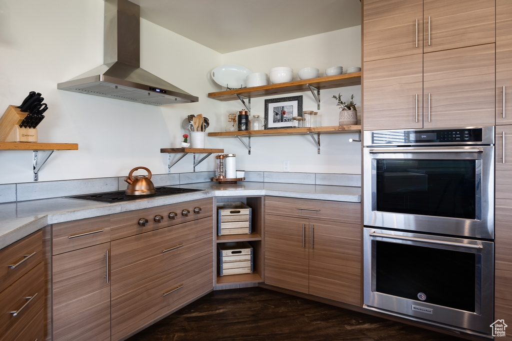 Kitchen featuring wall chimney exhaust hood, double oven, and dark hardwood / wood-style floors