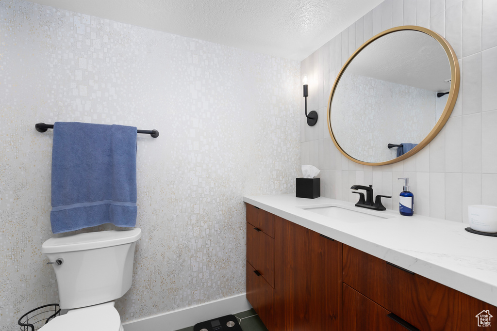 Bathroom featuring a textured ceiling, vanity, toilet, and tile flooring
