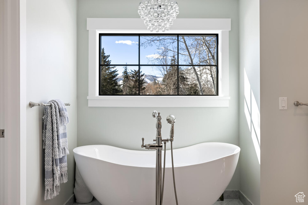Bathroom with a notable chandelier, plenty of natural light, and a washtub