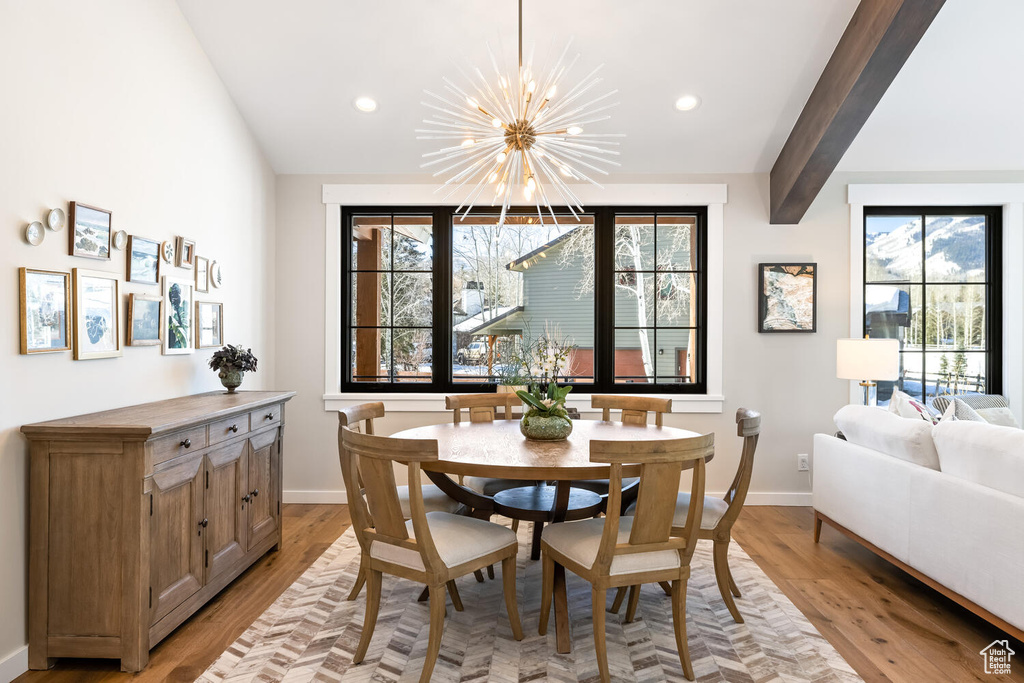 Dining room featuring beamed ceiling, light hardwood / wood-style floors, and a chandelier