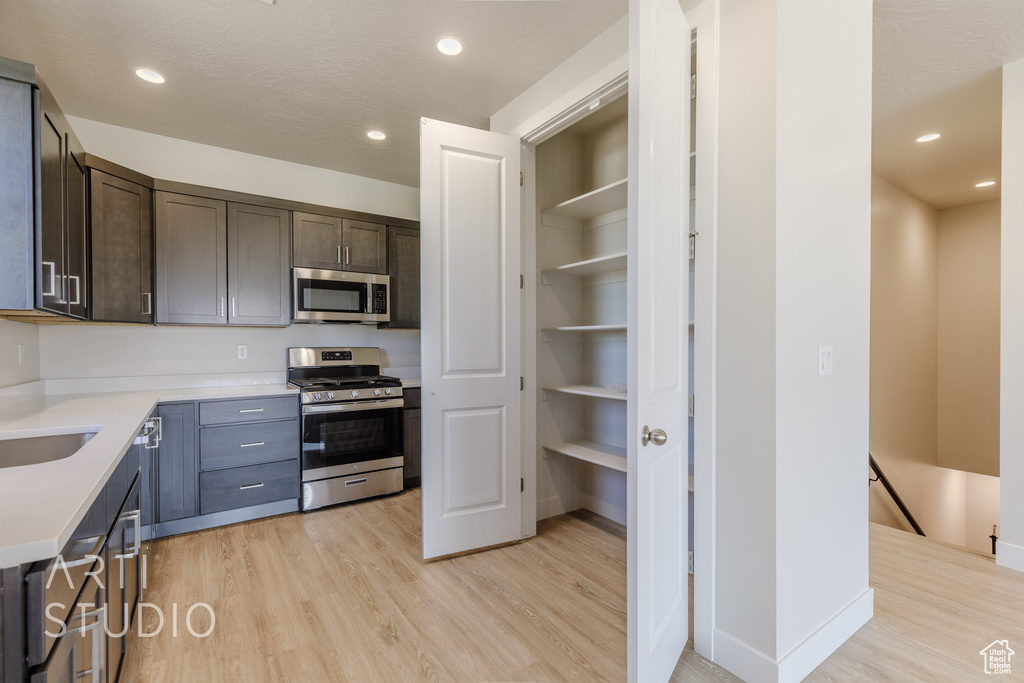 Kitchen featuring appliances with stainless steel finishes, dark brown cabinets, and light hardwood / wood-style floors