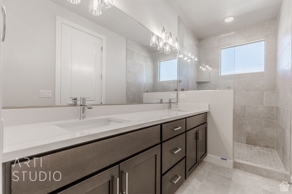 Bathroom with vanity, a tile shower, and tile patterned flooring