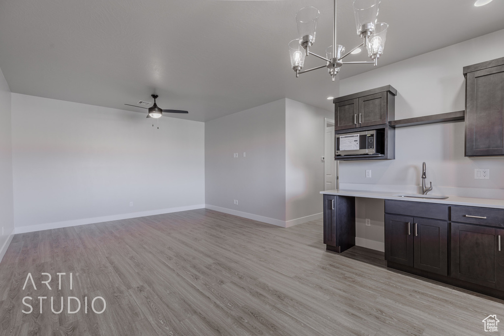 Kitchen featuring sink, dark brown cabinetry, ceiling fan with notable chandelier, and light hardwood / wood-style floors