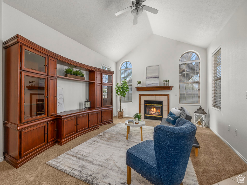 Living area featuring light colored carpet, a fireplace, vaulted ceiling, and ceiling fan