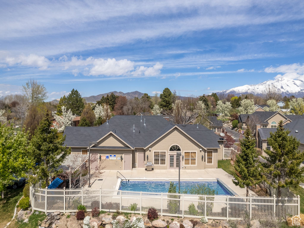 Rear view of property with a fenced in pool, a patio area, and a mountain view