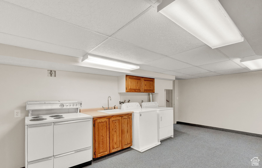 Kitchen featuring a drop ceiling, white electric range, separate washer and dryer, light carpet, and sink