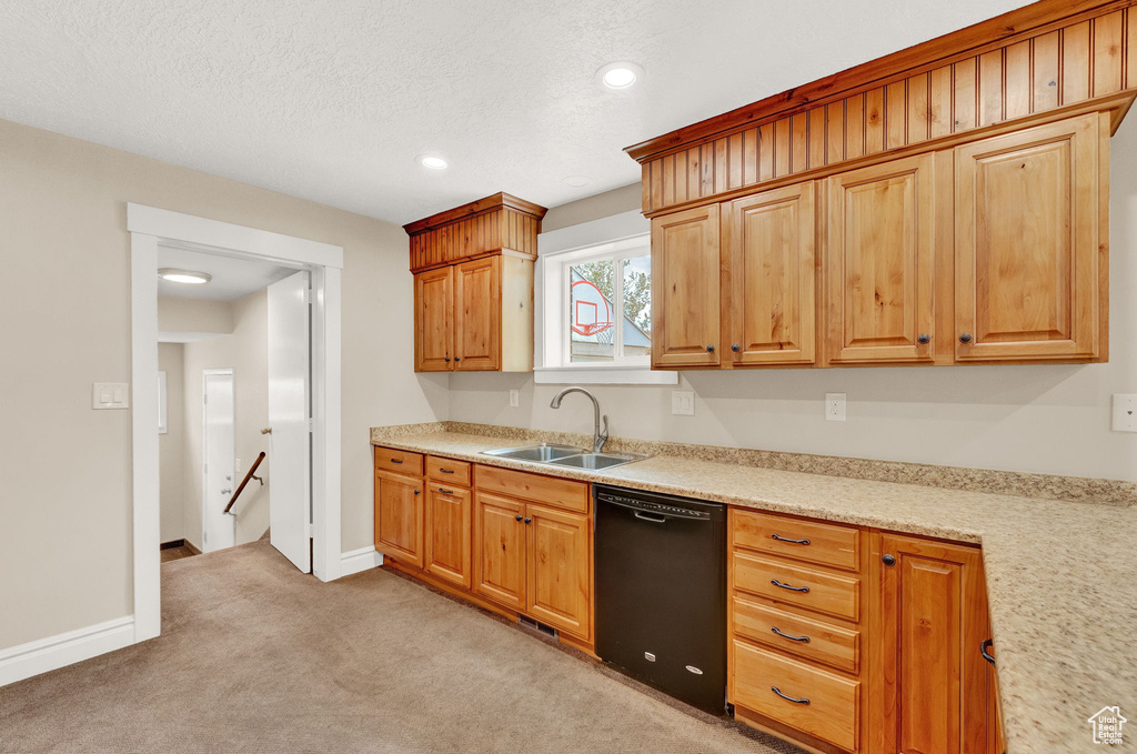 Kitchen with light stone counters, a textured ceiling, sink, dishwasher, and light colored carpet